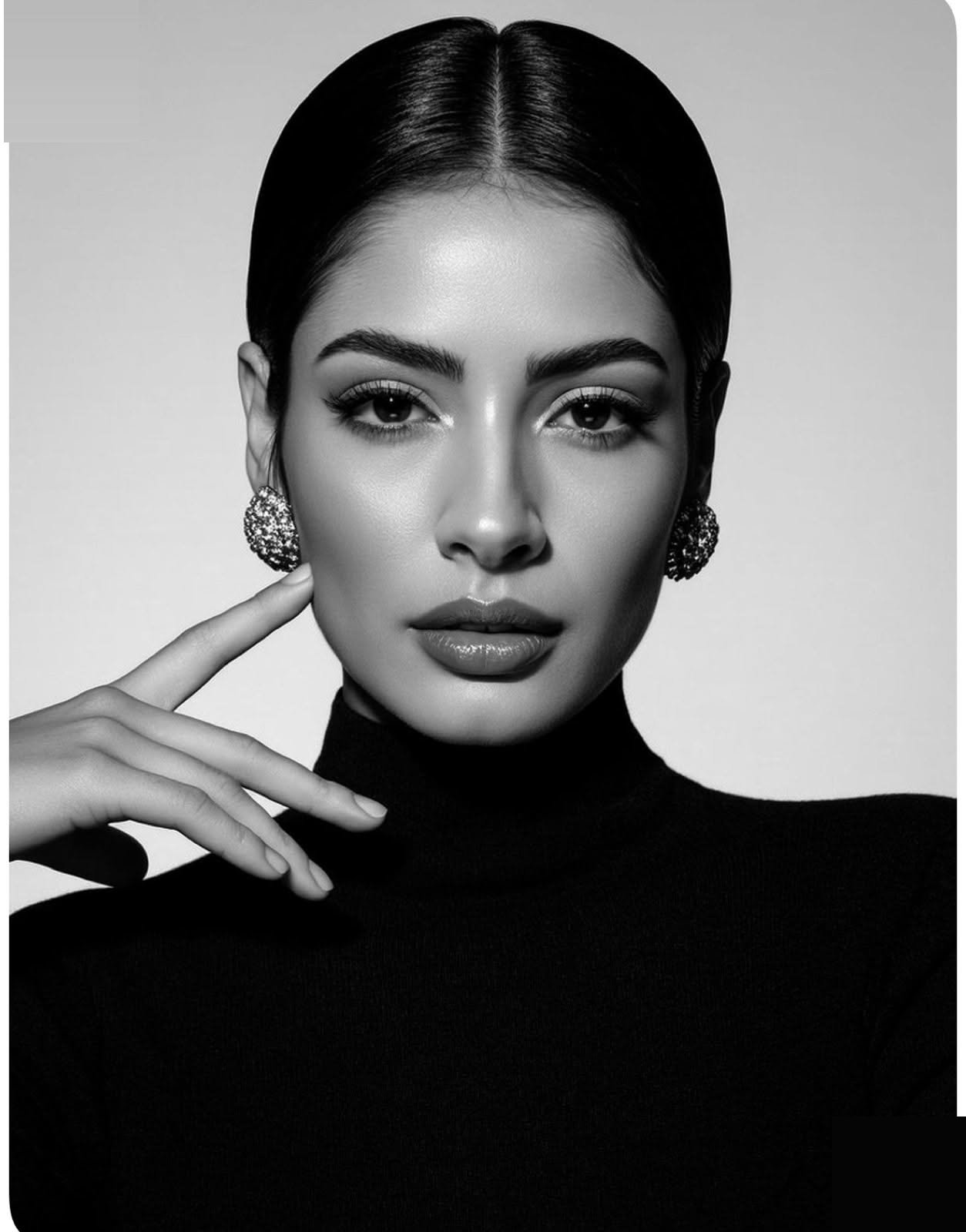 Black-and-white beauty close-up, hand at chin, statement drop earrings